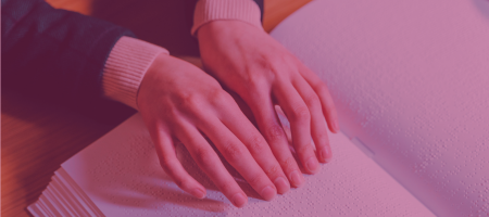 Hands reading a Braille book by touch, representing accessible library materials and services for visitors who are blind or have low vision.